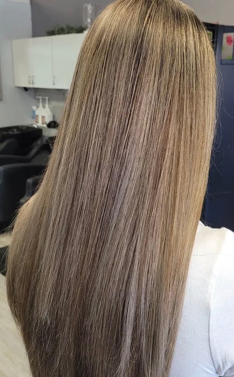 Back view of a woman with long, straight, light brown hair in a salon setting