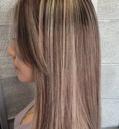 Side profile of woman with long straight hair featuring brown and blonde highlights