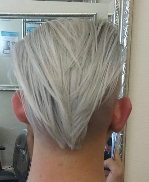 Back view of a woman with short, layered platinum blonde hair styled in a textured cut