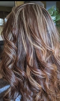 Long wavy hair with layered brown and blonde highlights in an indoor setting