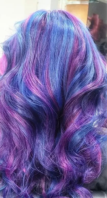 Back view of long wavy hair with vibrant purple, blue, and pink color gradient dye